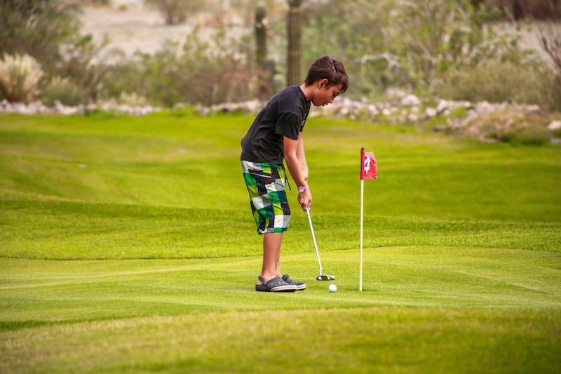 Niño jugando golf en putting course de TPC Danzante Bay Loreto